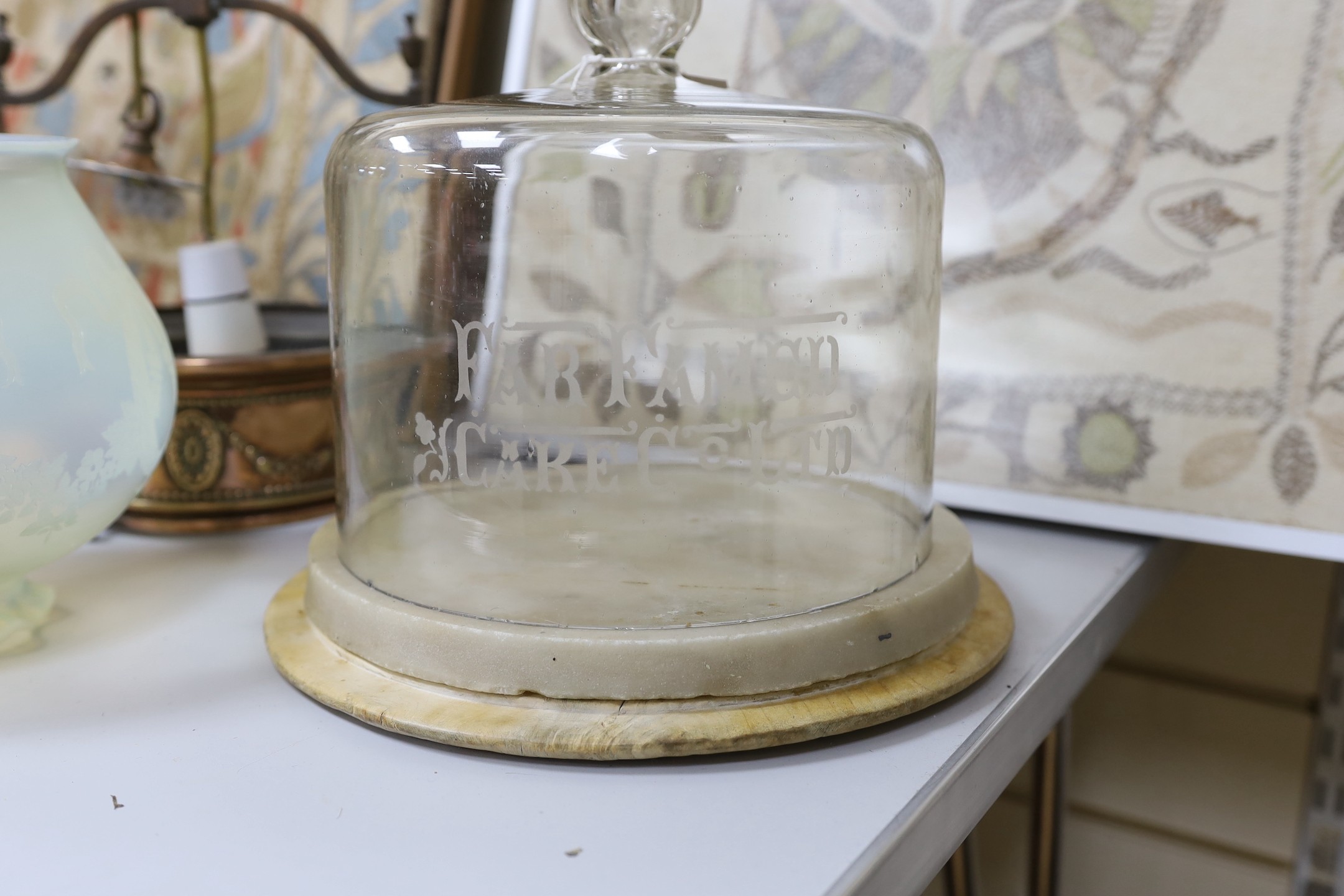 An embossed copper ceiling light with vaseline glass shade, and Far Famed Cake Co. cake stand and domed cover